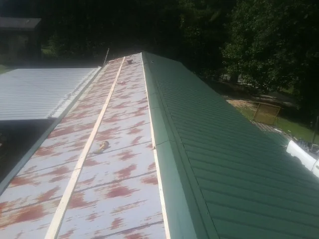 Old rusted panels beside newly installed green metal roofing — Wind Damage Roof Repair by Roofing Brothers in La Puente