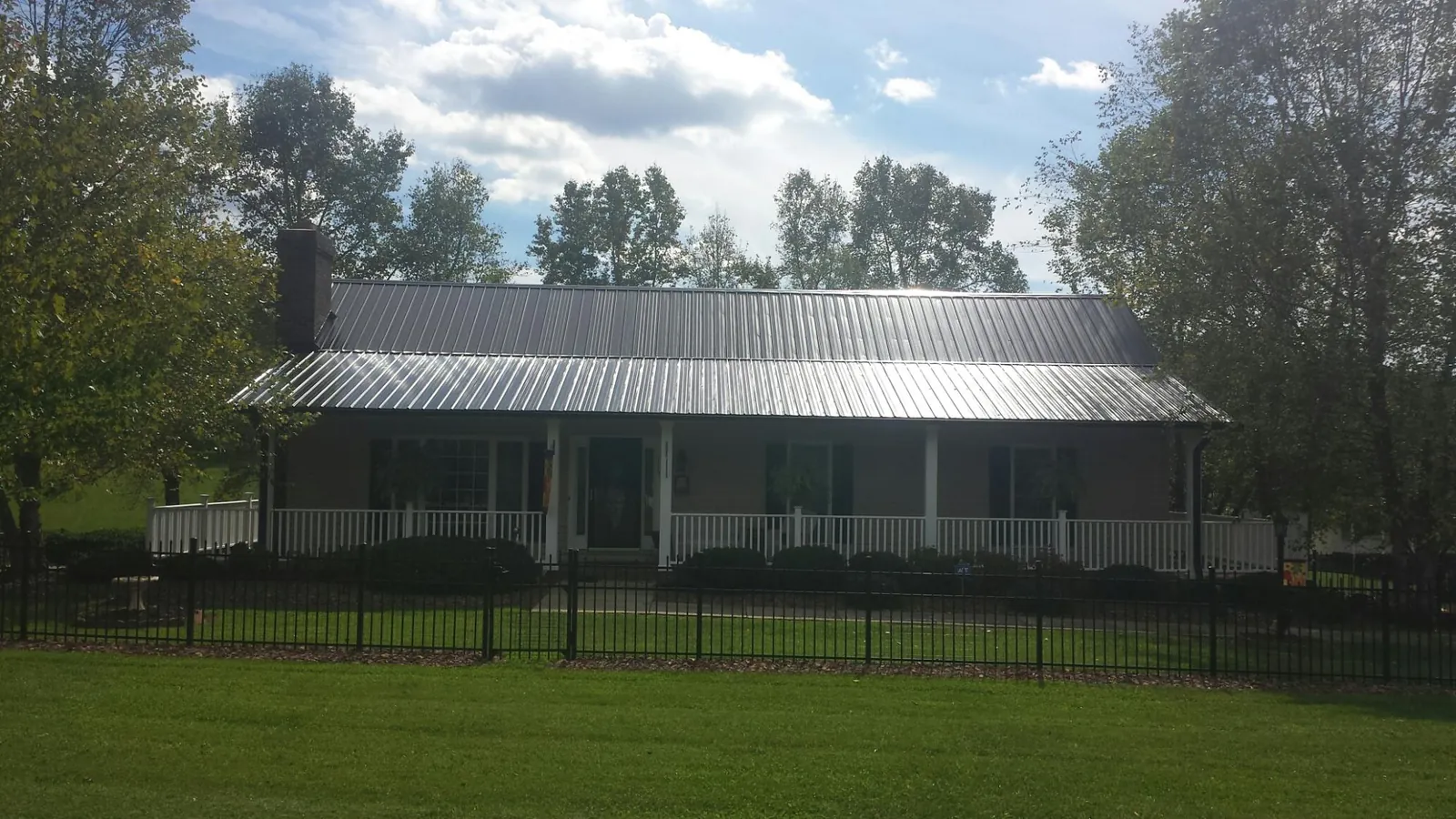 Gray metal roof on a brick ranch with a full width front porch — Gutter Guard Installation work by our crew in La Puente