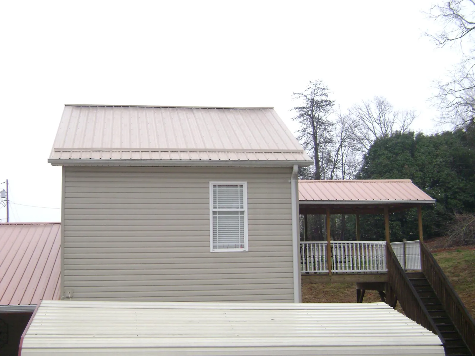 Tan metal roofs on a two story addition and attached porch, from a Roof Replacement job in La Puente